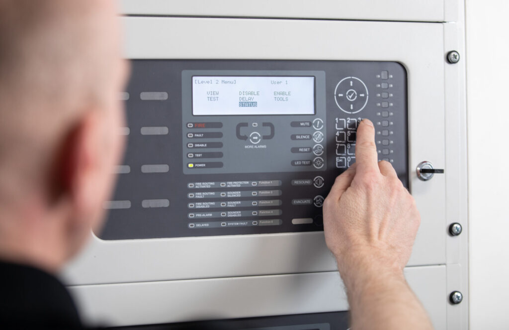 Someone pressing a button on a fire alarm control panel